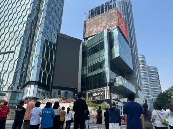 诚信优配 大屏幕转播阅兵仪式路人驻足 爱国情怀激荡心间